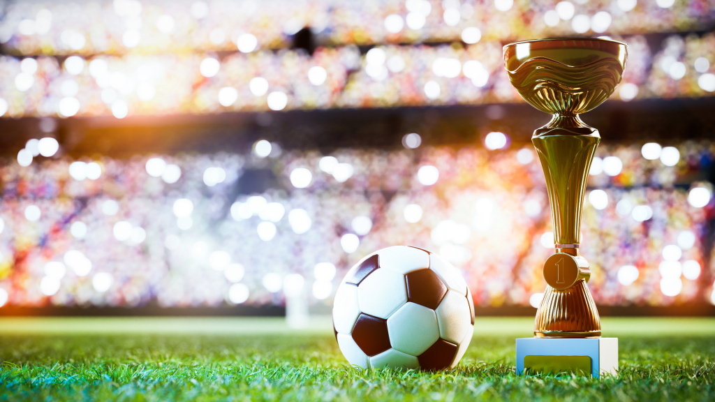 World Cup trophy and soccer ball on soccer field inside a stadium