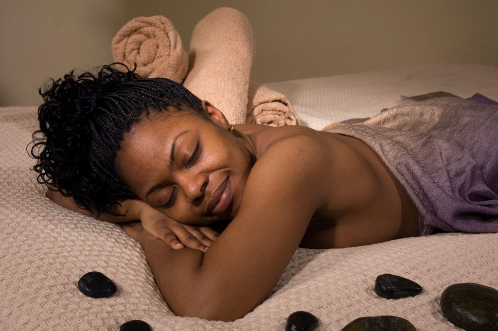 Black woman restfully laying on a massage table with her eyes closed